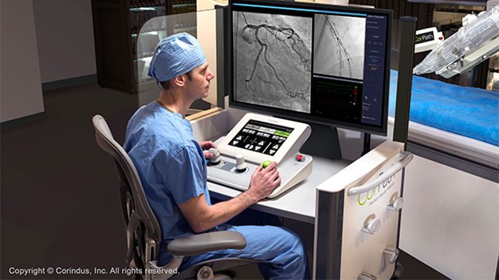 外科医生坐在桌子前，用一种设备浏览他面前屏幕上显示的图像。