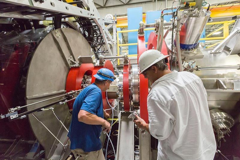 两个人，戴着安全帽，在核聚变反应堆上工作。