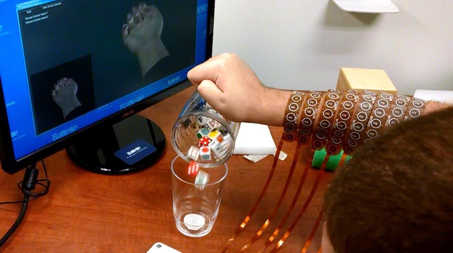 右上角的电脑屏幕显示了Burkhart的手的头像，他的手在握紧的位置，这是他的手(屏幕中间)抓住杯子的方式。他正把杯子里的方块倒进玻璃杯里。