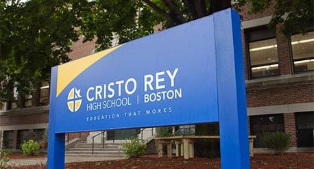 克里斯托·雷伊学校外面的蓝色白字招牌。标牌上写着克里斯托雷高中，波士顿-有效的教育。图片来源:Cristo Rey高中
